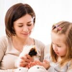 a women with her kid trying to gain trust of guinea pig